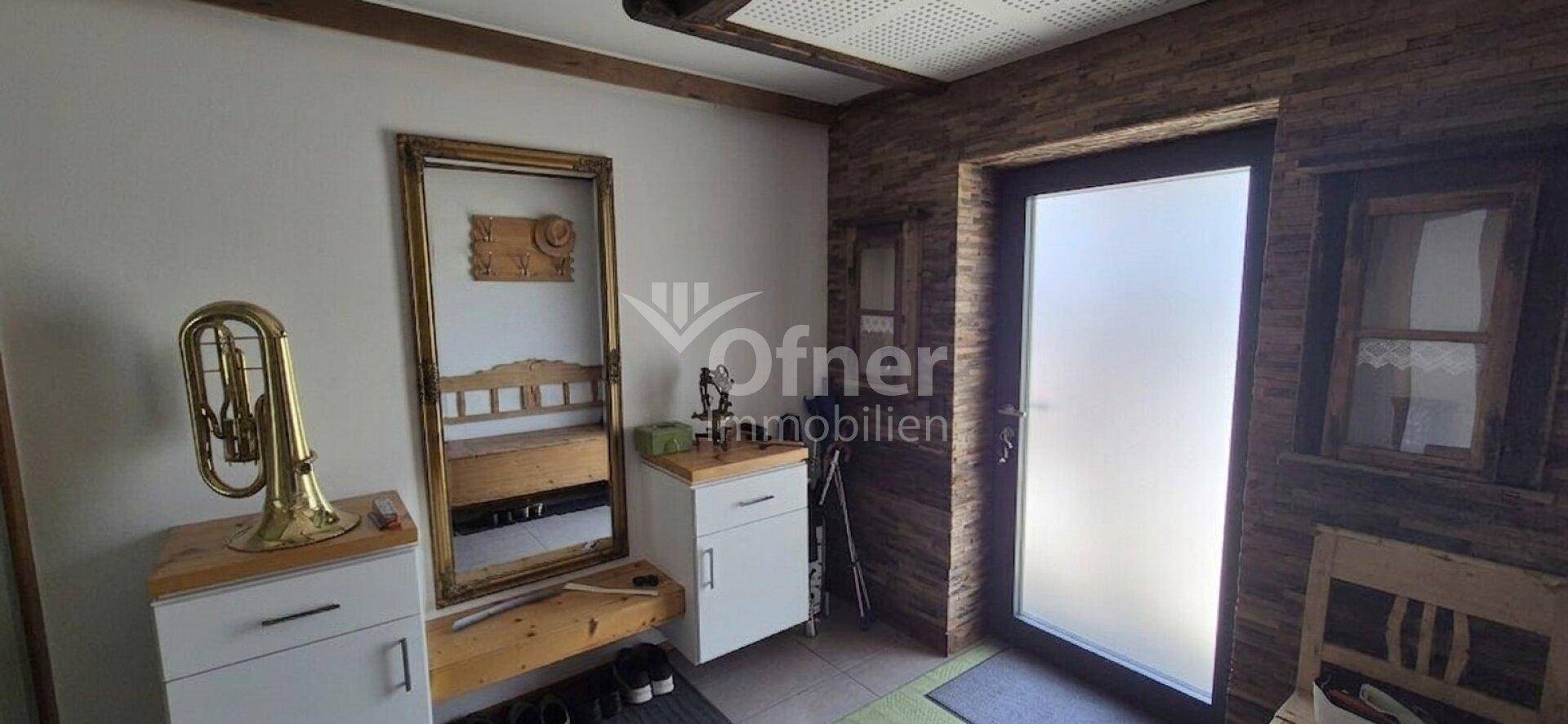 Eingangsbereich mit Holzakzenten, Spiegel und Garderobe.