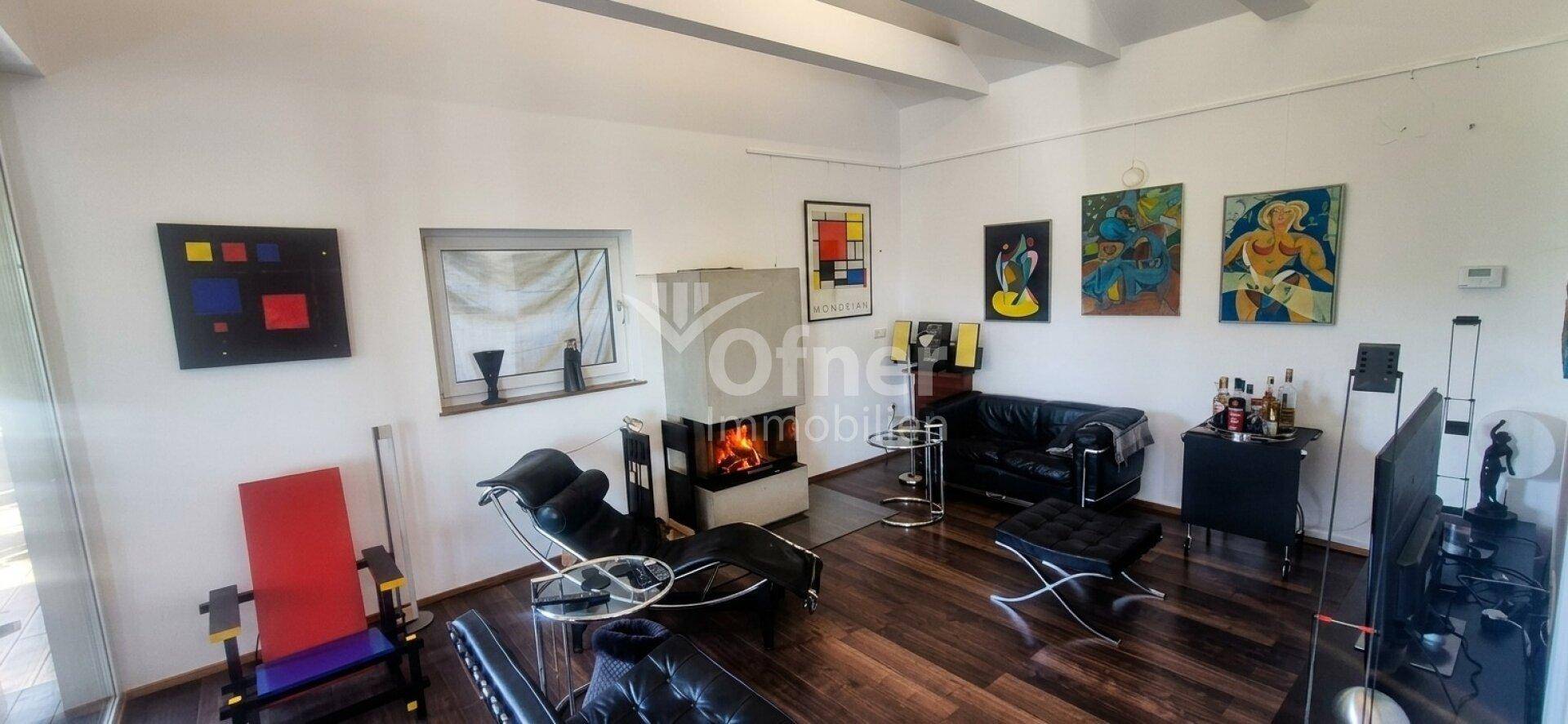 Gemütliches Wohnzimmer mit Kamin, dunklen Möbeln und Kunstwerken an den Wänden.