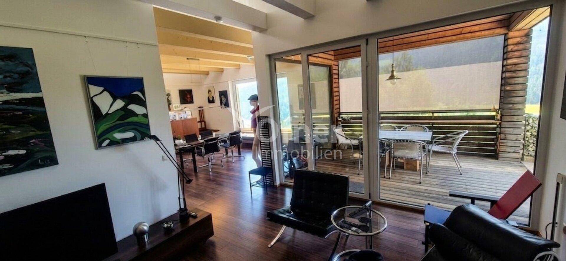 Wohnzimmer mit Zugang zur überdachten Terrasse und Blick ins Grüne.