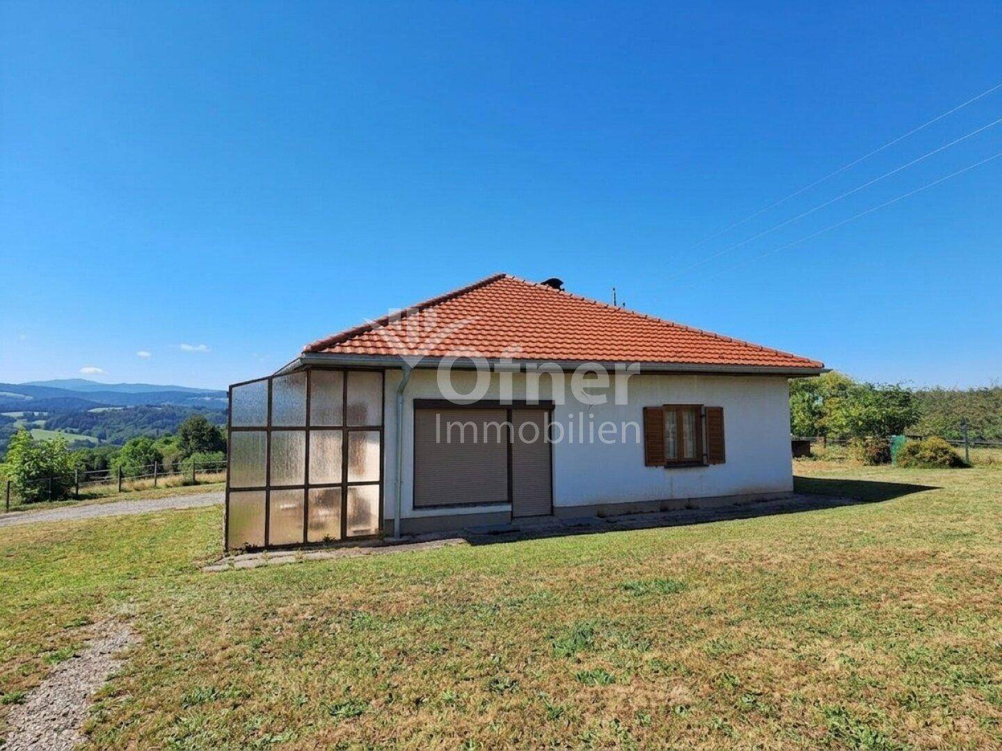 Seitenansicht des Hauses mit einem Anbau und weitem Blick über die grüne Landschaft.