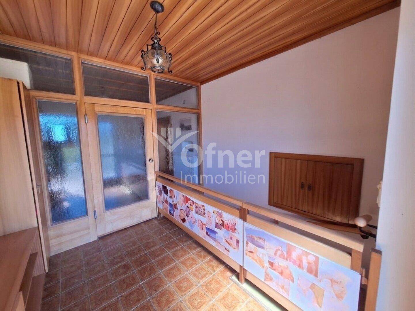 Eingangsbereich mit Holzvertäfelung an Decke und Wänden sowie gefliestem Boden.