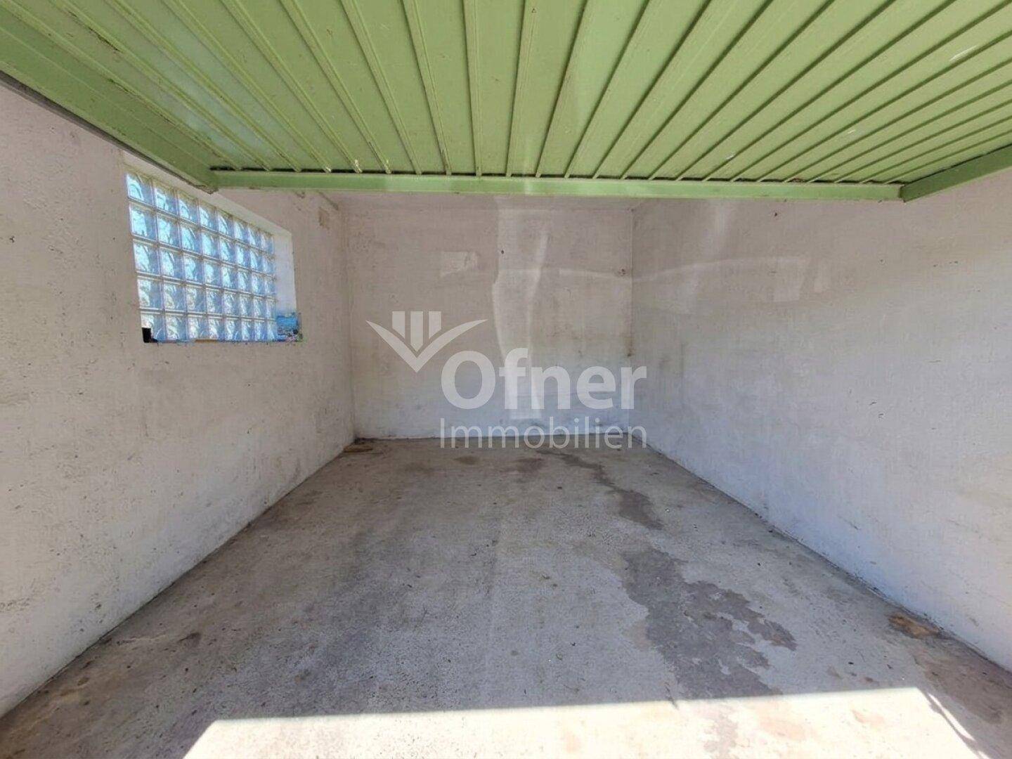 Garage mit Betonboden, Glasbausteinfenster und grün gestrichener Decke.
