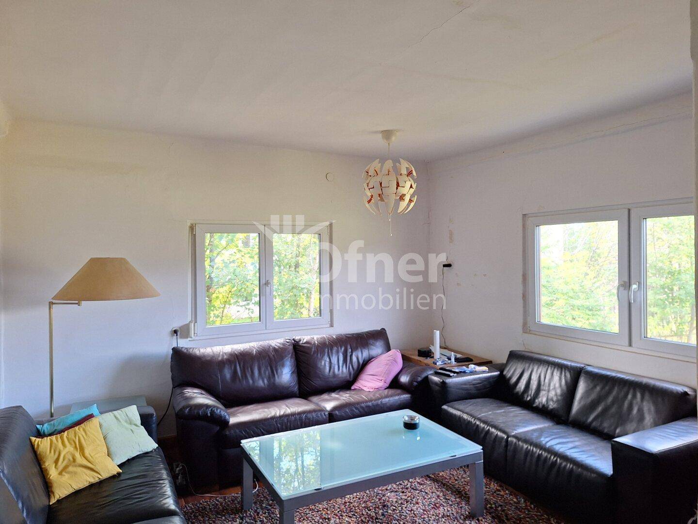 Gemütliches Wohnzimmer mit Ledersofas, Couchtisch und Blick ins Grüne durch große Fenster.