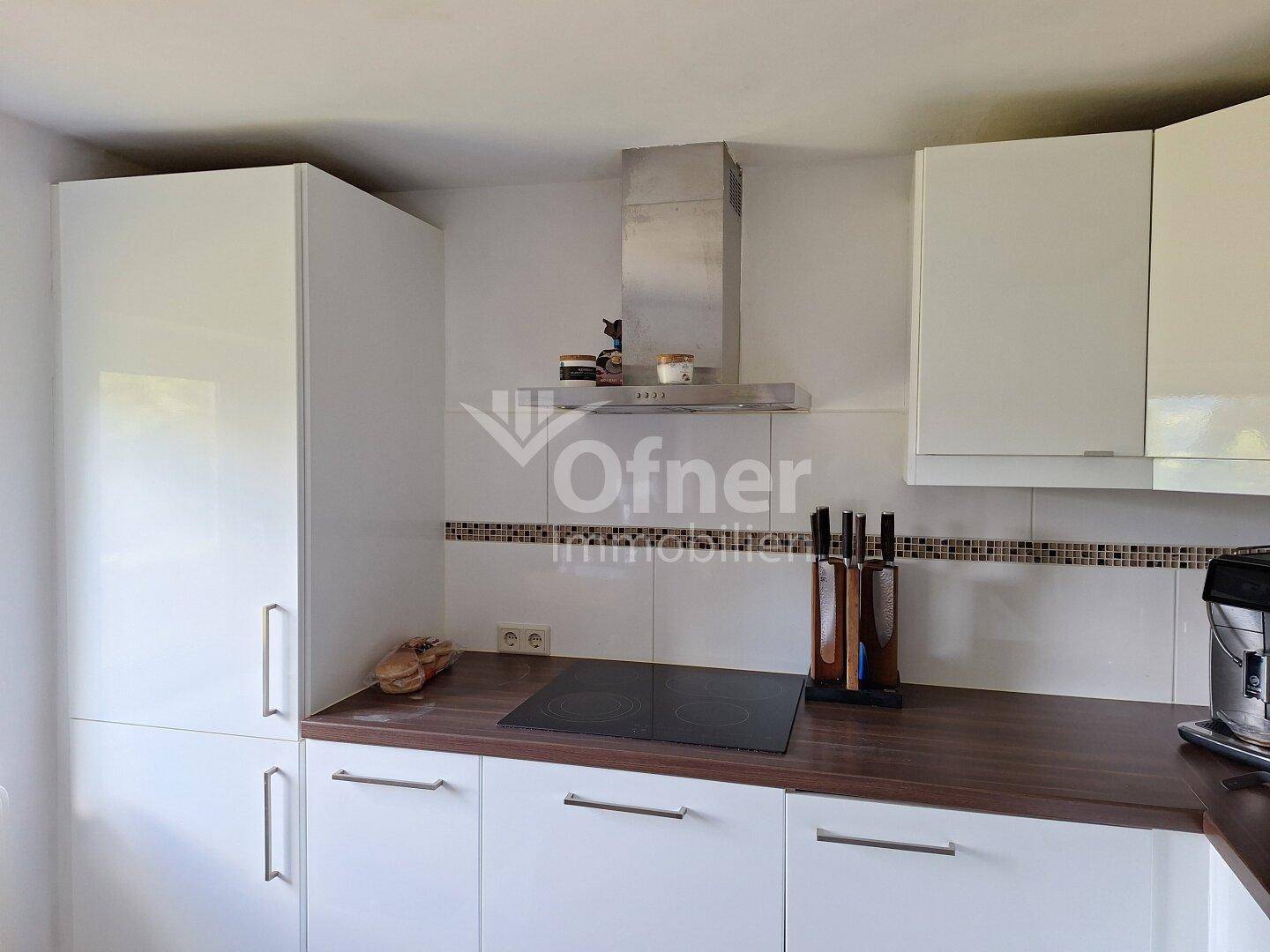 Moderne Küche mit weißen Hochglanzschränken, dunkler Arbeitsplatte und Induktionskochfeld.