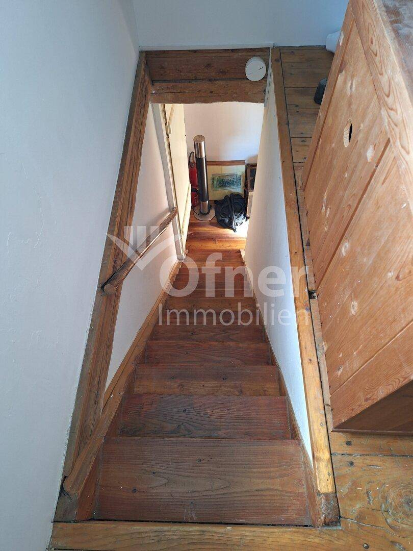 Rustikale Holztreppe führt in einen weiteren Bereich des Hauses mit Holzboden.