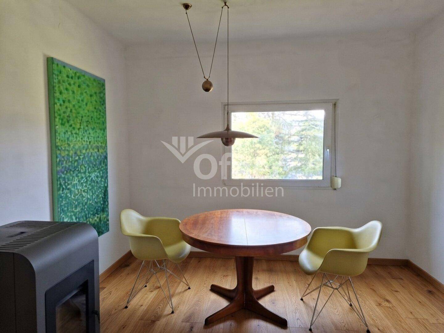 Heller Essbereich mit Holztisch, modernen Stühlen und einem Holzofen für gemütliche Wärme.