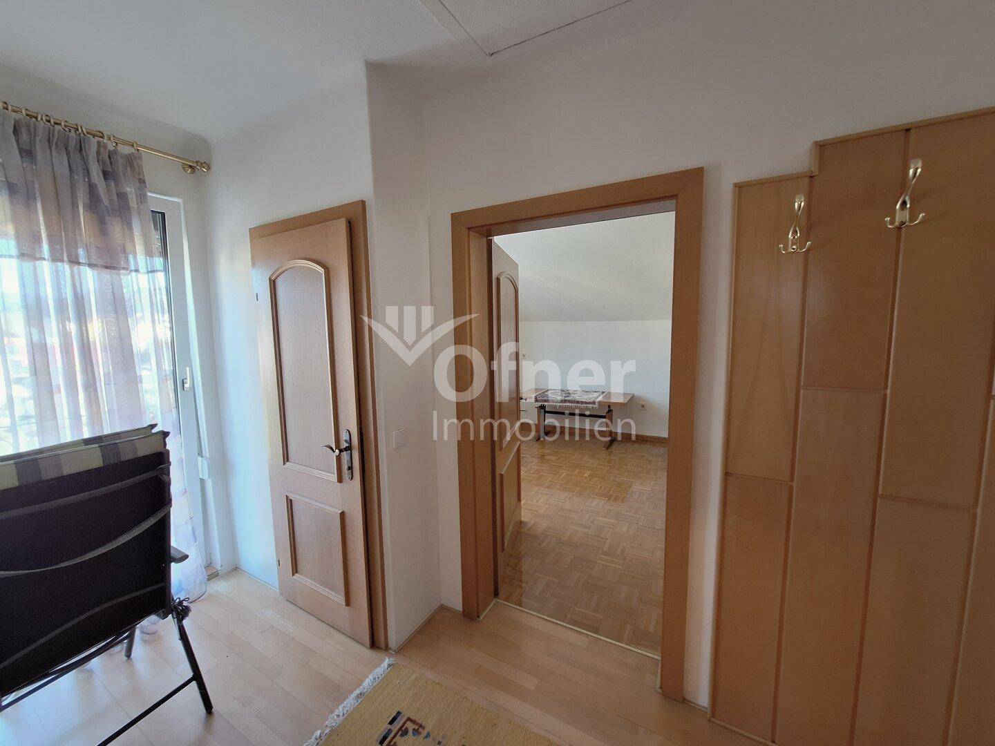 Flur mit mehreren Türen und einem Blick in ein angrenzendes Zimmer im Dachgeschoss.