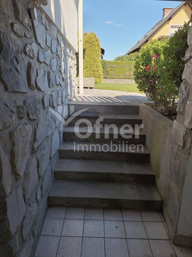 Eingang zum Keller über eine Betontreppe, umgeben von einer Natursteinverkleidung.
