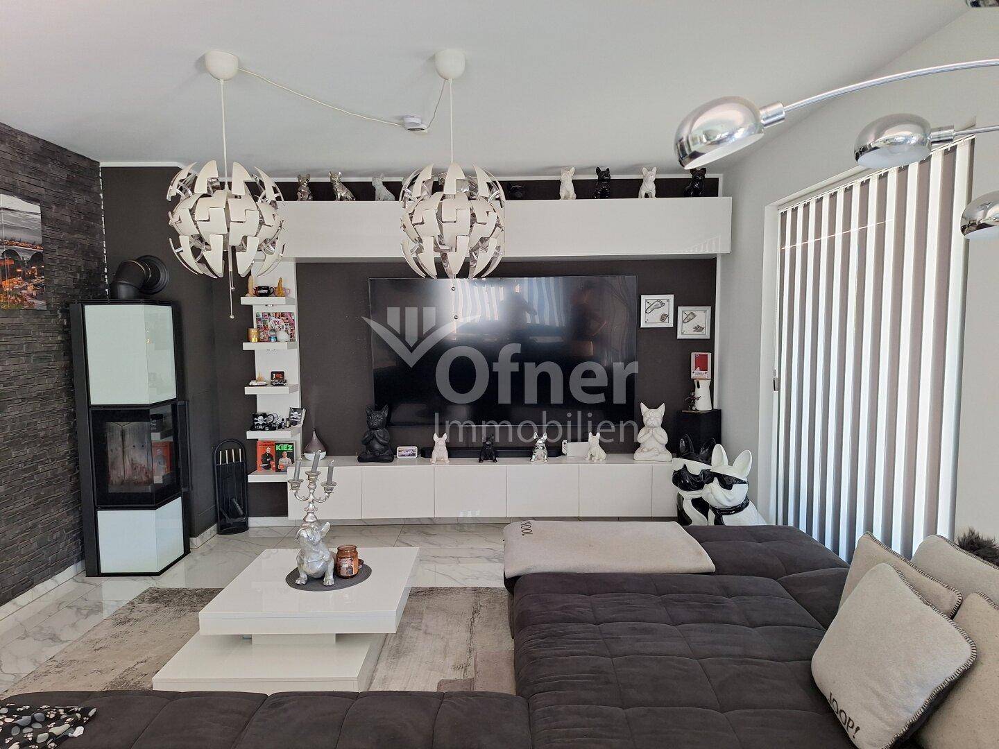 Modernes Wohnzimmer mit großem Ecksofa, Kaminofen und Entertainment-Center mit Fernseher.
