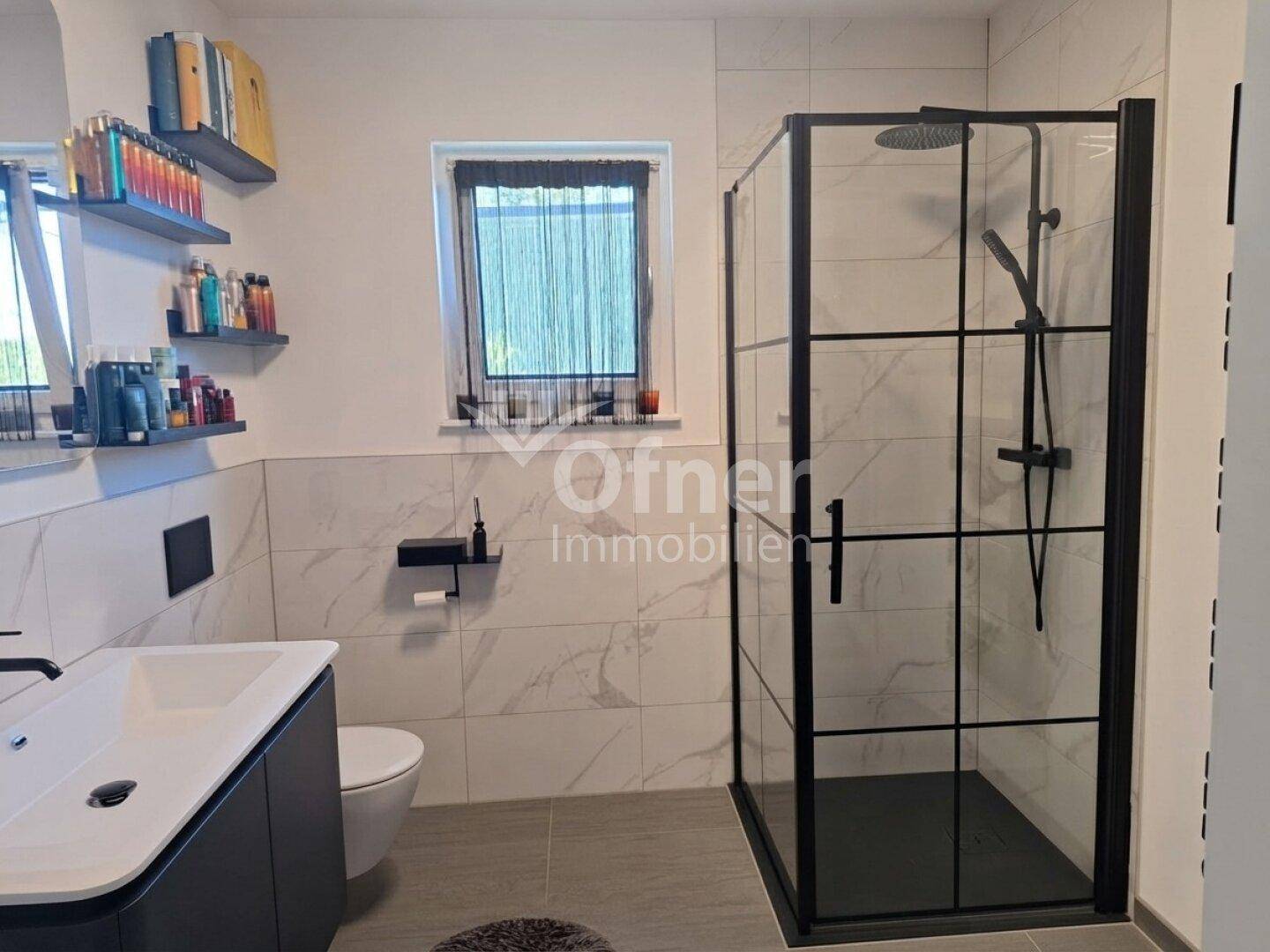 Modernes Badezimmer mit begehbarer Dusche, Wand-WC und stilvollen Fliesen in Hellgrau und Weiß.