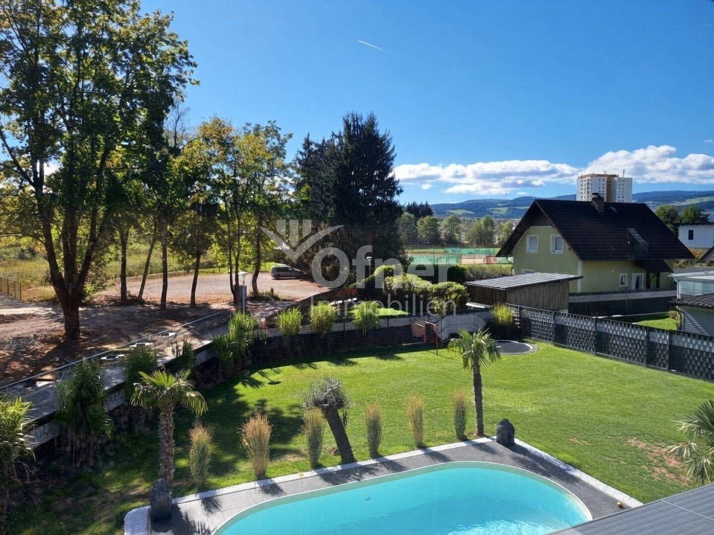 Weitläufiger Gartenbereich mit Pool, Rasenfläche und Blick auf die umliegende Landschaft und Berge.