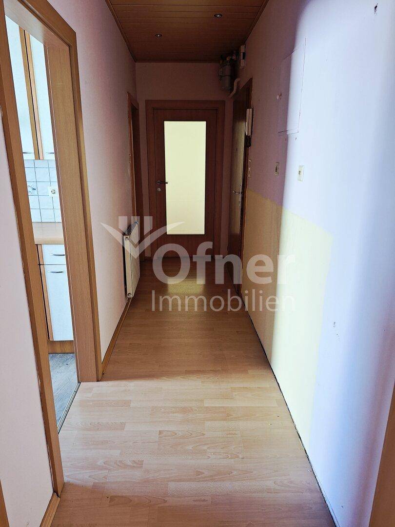 Langer Flur mit Laminatboden und Holztäfelung an der Decke.