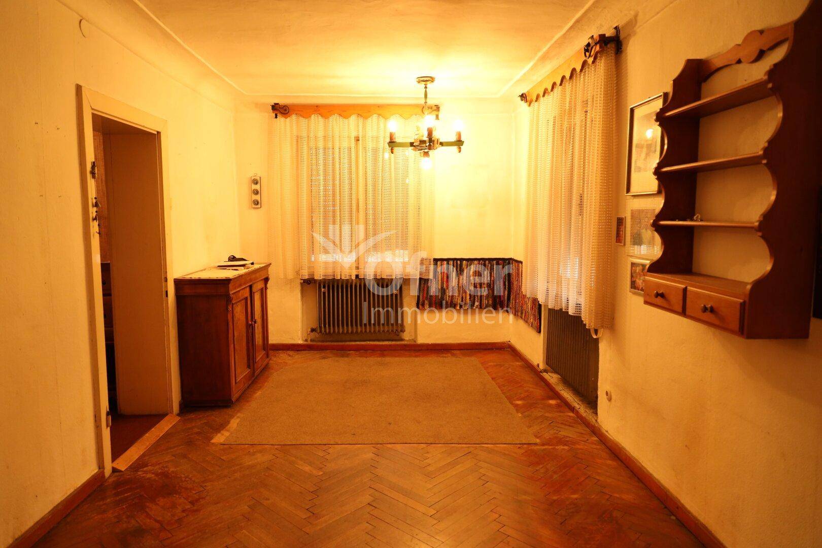 Gemütlicher Essbereich mit Holzboden, traditionellen Möbeln und einem verzierten Schrank.