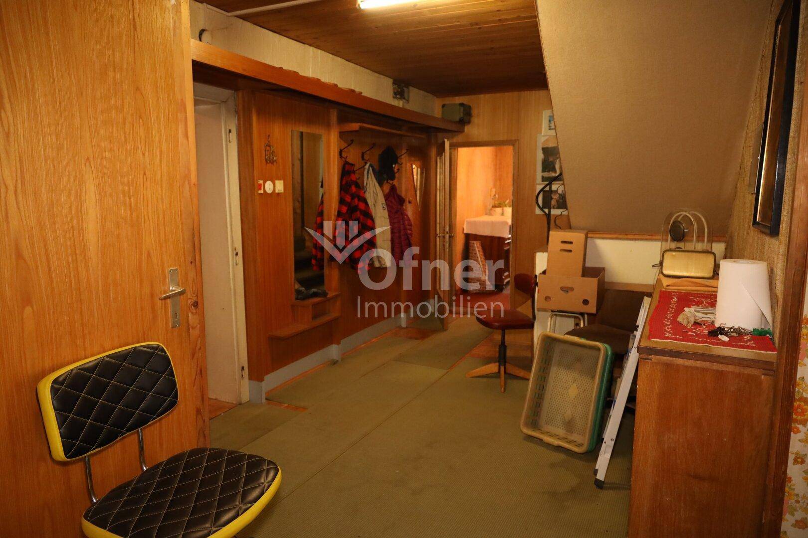 Langer Flur mit Holzverkleidung, Teppichboden und Garderobe.