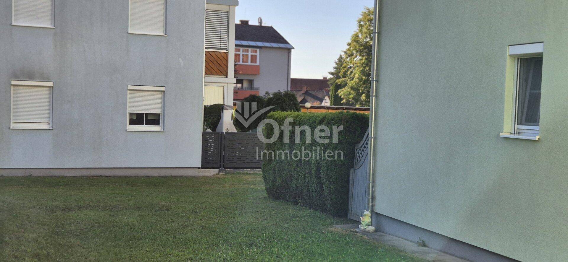 Außenansicht eines Wohngebäudes mit Rollläden und einem gepflegten Rasenbereich.