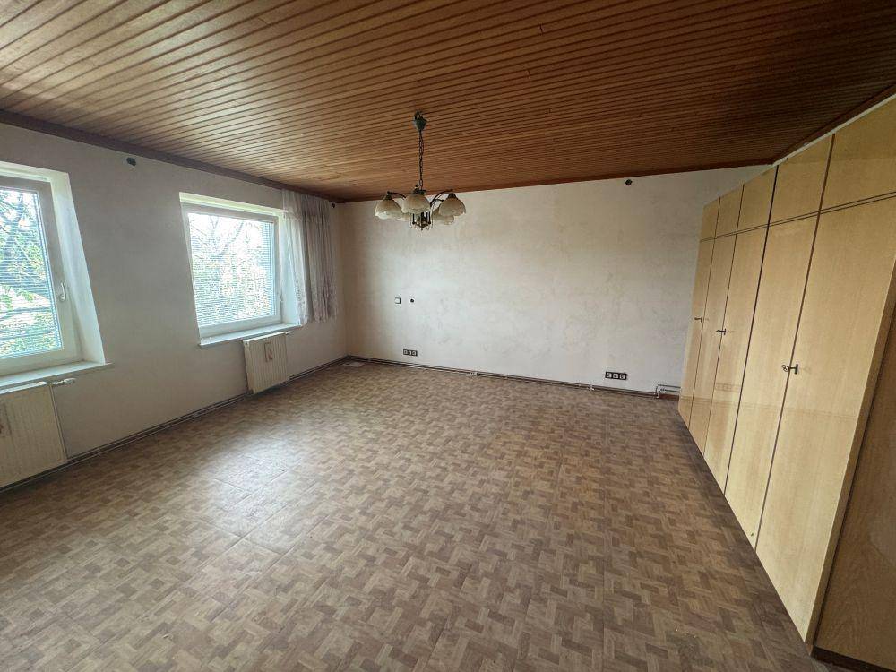 Schlafzimmer mit gemustertem Boden, Holzdecke und großen Einbauschränken entlang einer Wand.