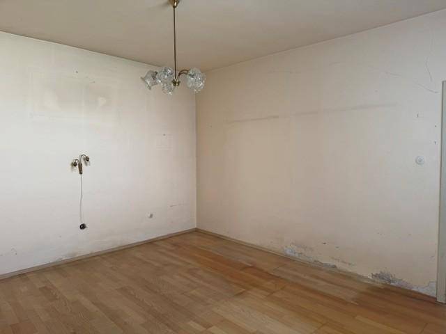 Leeres Zimmer mit hellem Holzfußboden und weißen Wänden, bereit zur individuellen Gestaltung.