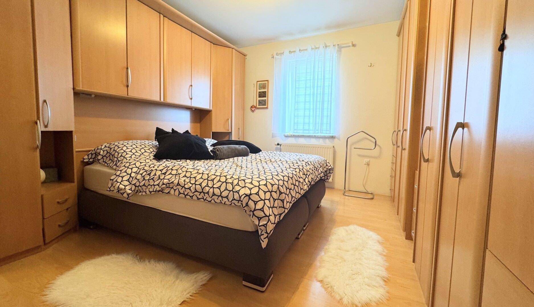 Gemütliches Schlafzimmer mit Doppelbett, Einbauschränken und Laminatboden.
