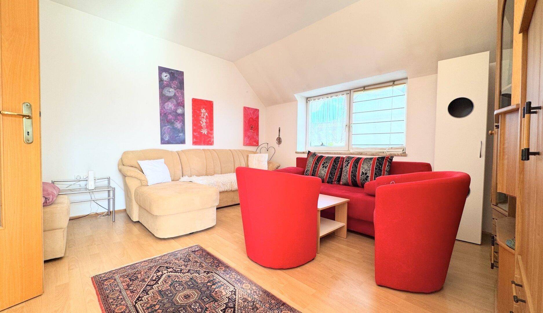Helles Wohnzimmer mit bequemen Sofas, Holzboden und farbenfroher Dekoration.