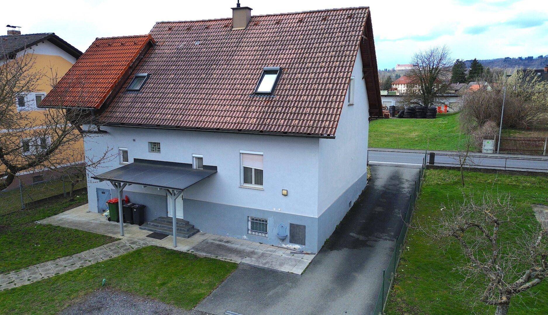 Rückansicht des Hauses mit überdachtem Eingangsbereich und großem Gartenbereich.