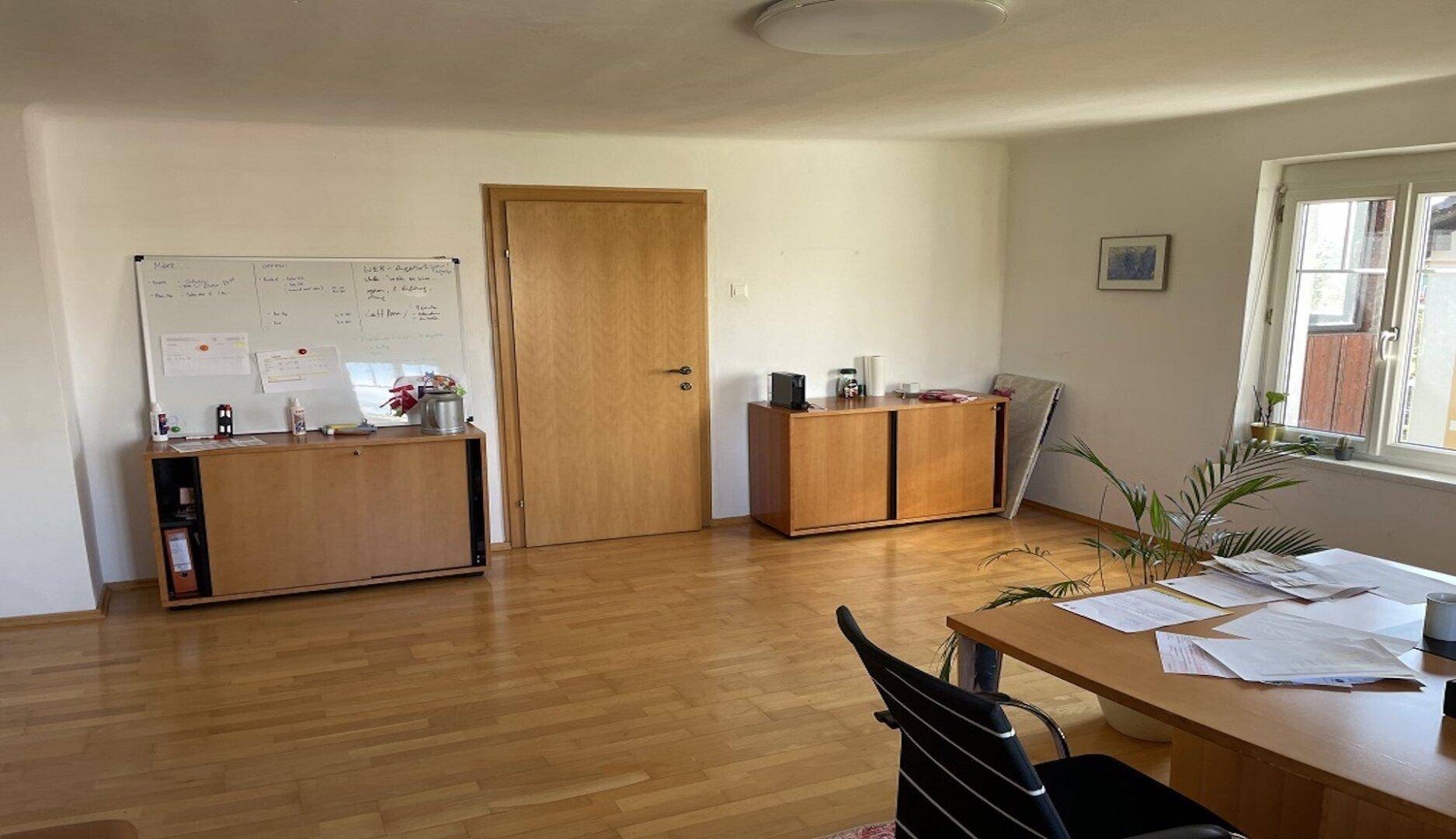 Helles Büro mit Holzboden, Schränken und einem Whiteboard, ideal für produktives Arbeiten.