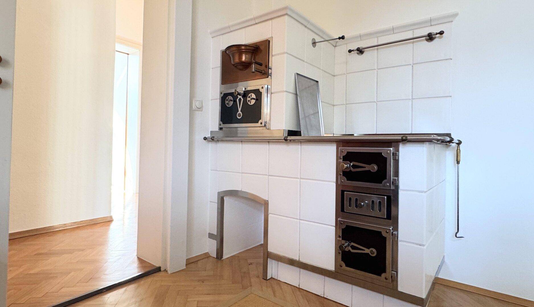 Detailansicht eines traditionellen Kachelofens in der Küche mit integrierten Backfächern und Metallbeschlägen.