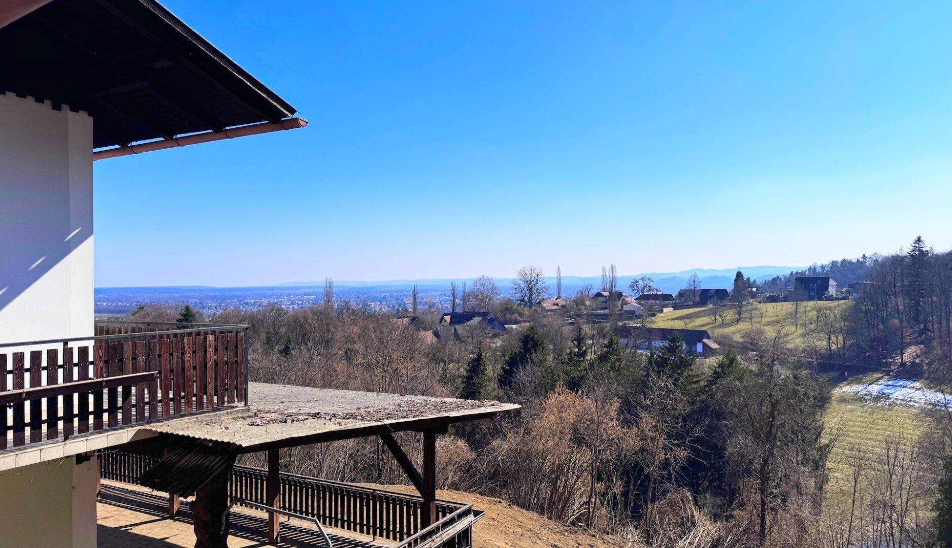 Aussicht von der Terrasse auf die umliegende Natur und die entfernte Stadtkulisse.