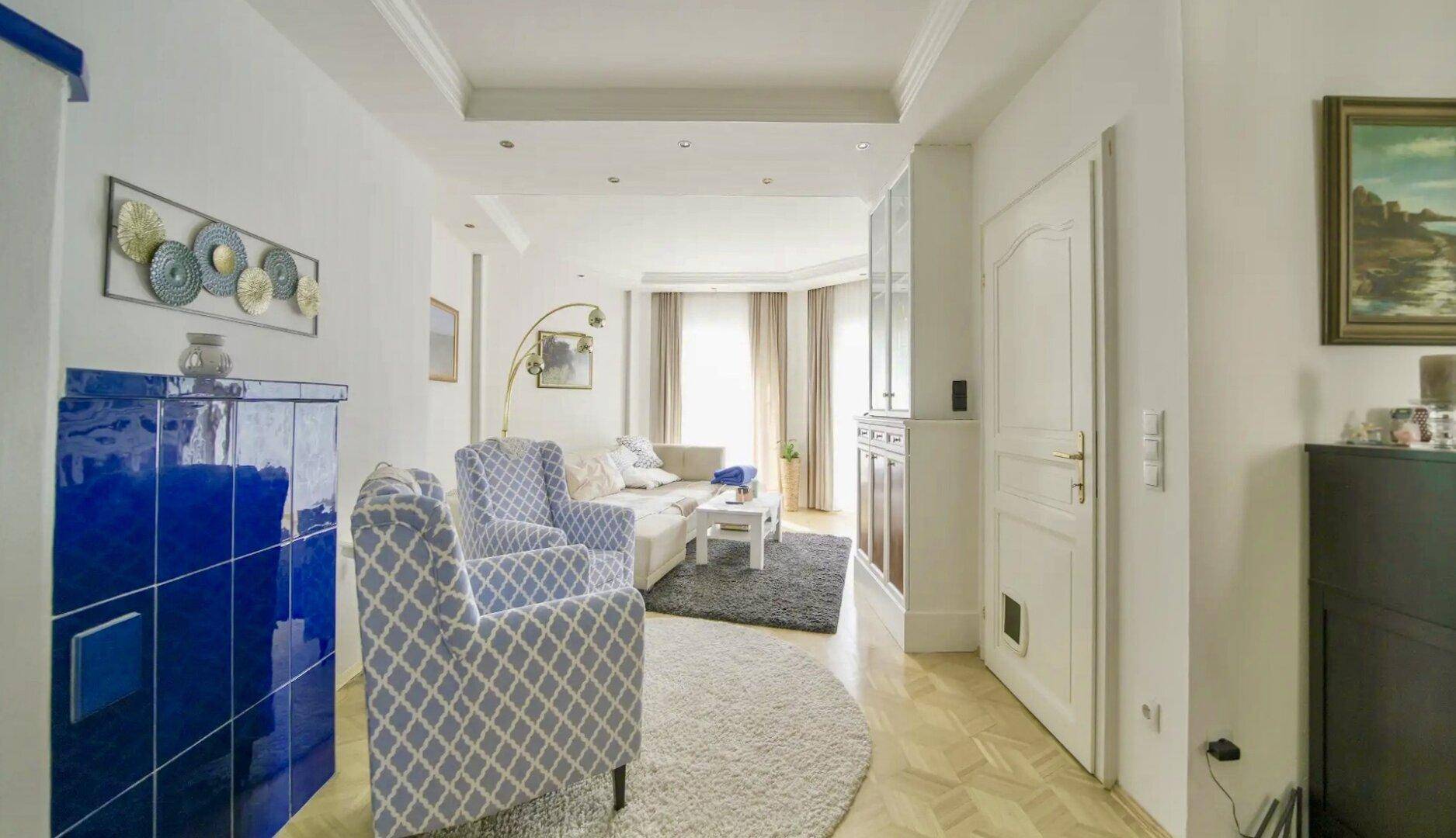 Stilvolles Wohnzimmer mit blauem Kachelofen, Parkettboden und heller, einladender Atmosphäre.