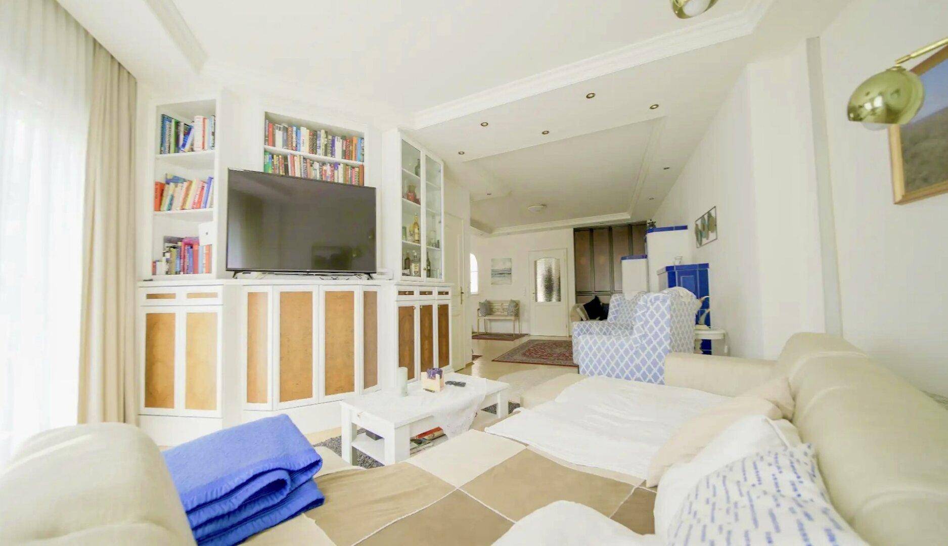 Wohnzimmer mit integrierten Bücherregalen und Fernseher, bietet eine helle und funktionale Wohnatmosphäre.