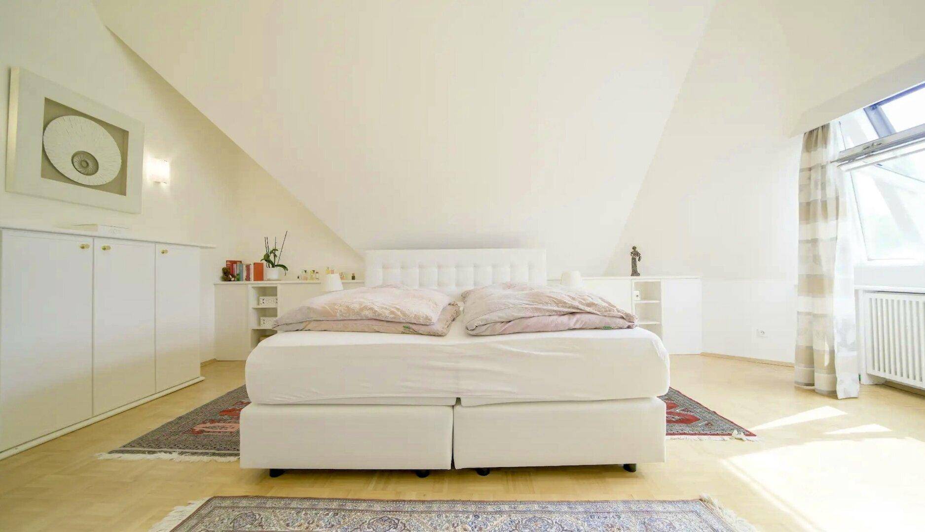 Helles Schlafzimmer im Dachgeschoss mit Dachschrägen, Doppelbett und praktischen Einbauschränken.