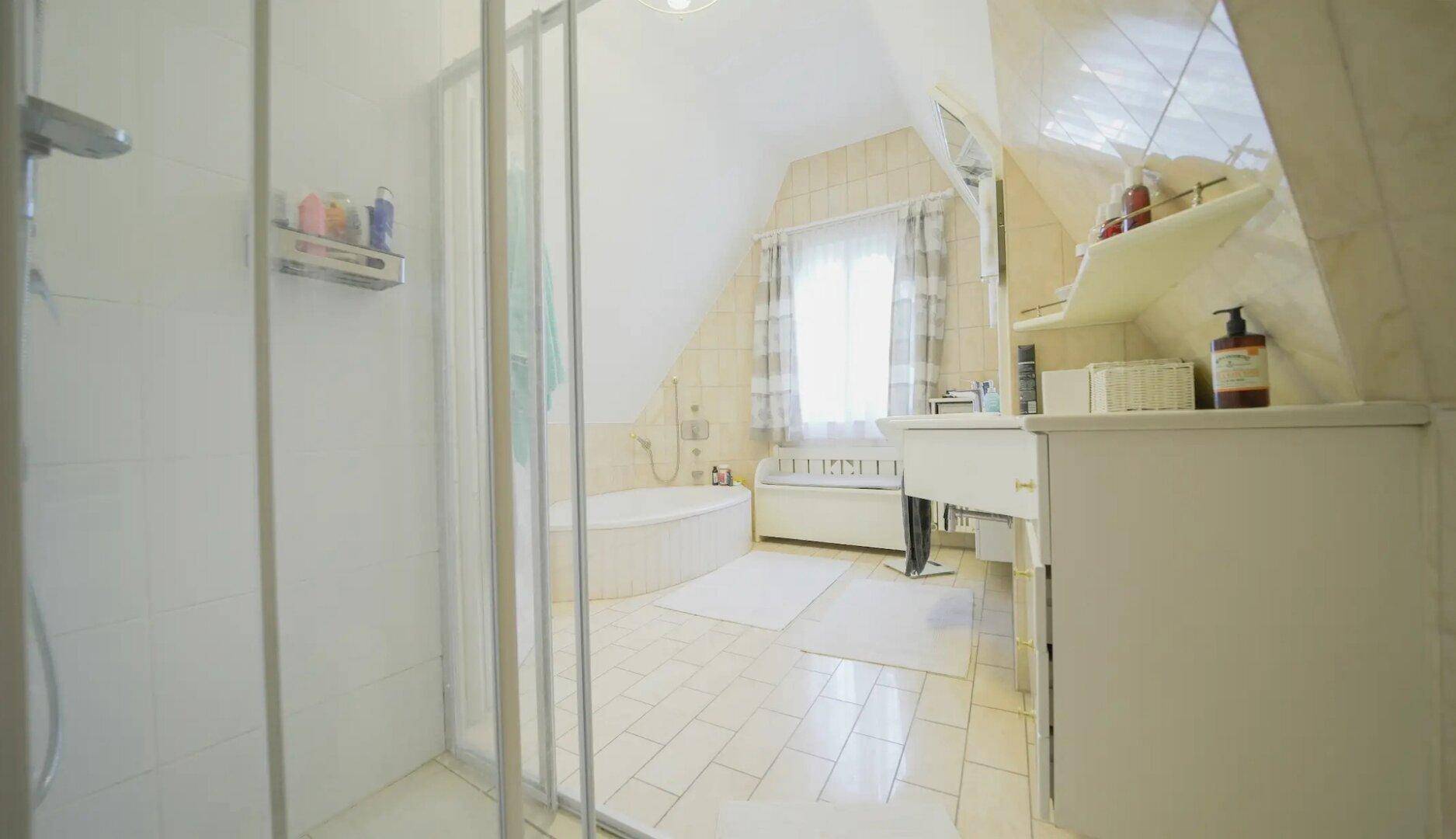 Helles Badezimmer im Dachgeschoss mit Dachschrägen, Duschkabine und Badewanne.