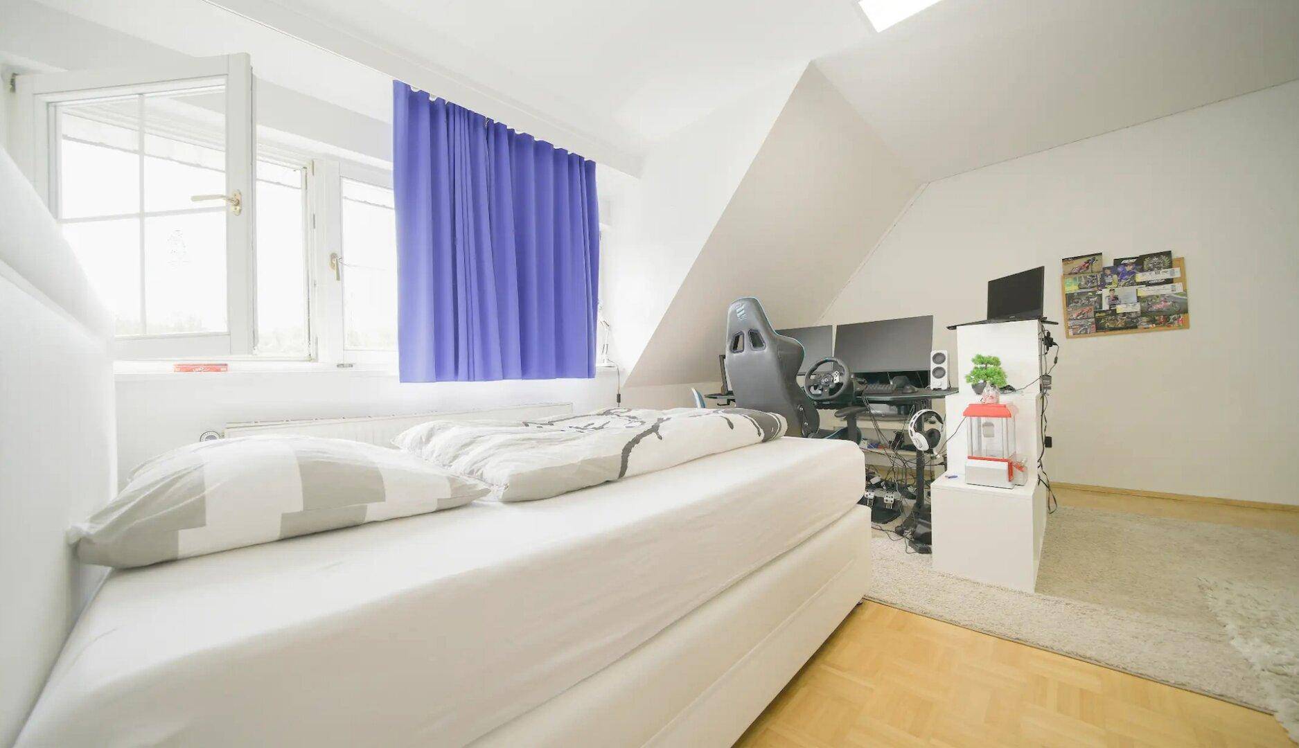 Modern eingerichtetes Schlafzimmer mit Schreibtischbereich und großem Fenster für viel Tageslicht.