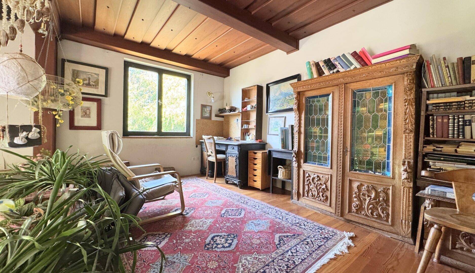 Gemütliches Arbeitszimmer mit Holzbalkendecke, Parkettboden und antiken Möbeln.
