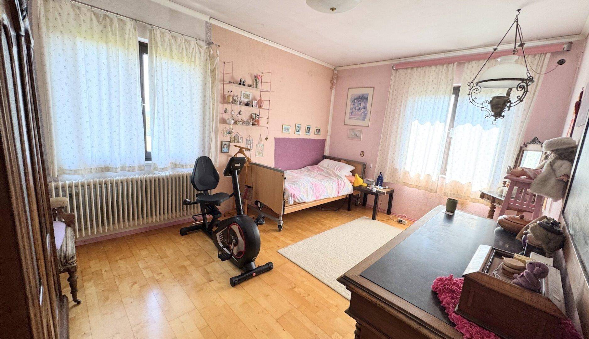 Helles Schlafzimmer mit rosa Wänden, Holzfußboden und großem Fenster.