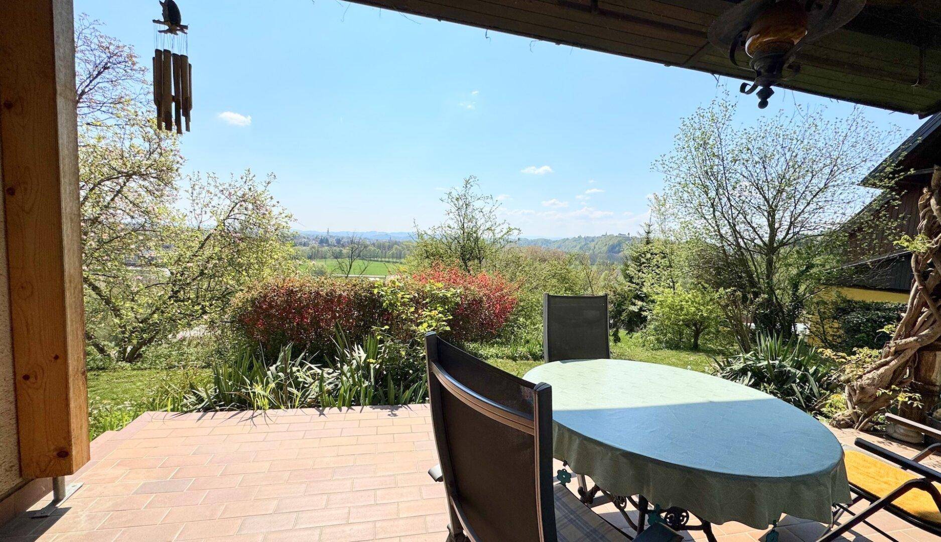 Überdachte Terrasse mit Sitzgelegenheiten und weitem Blick über die Landschaft.