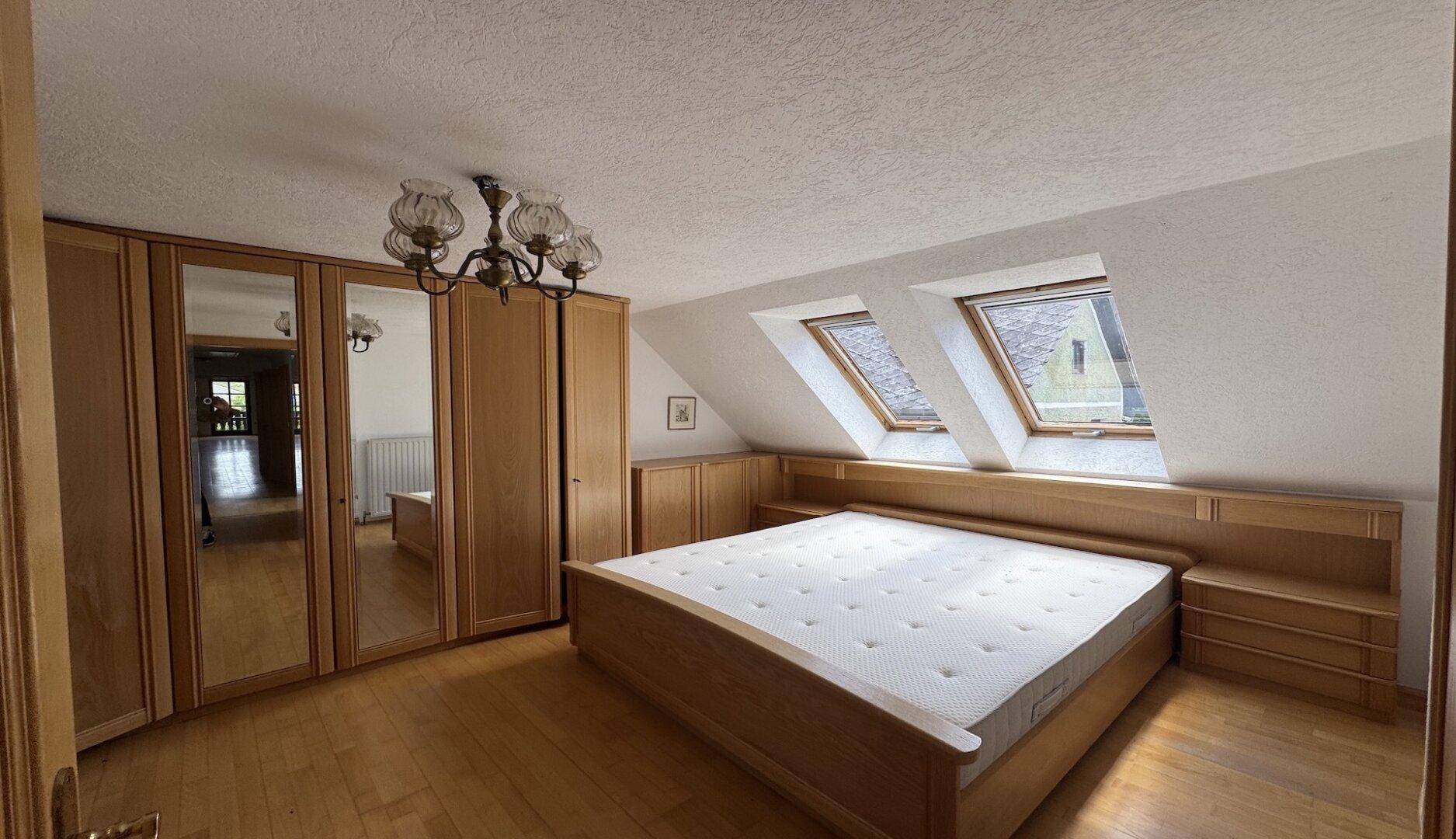 Helles Schlafzimmer im Dachgeschoss mit Doppelbett, Kleiderschrank und Dachfenstern.