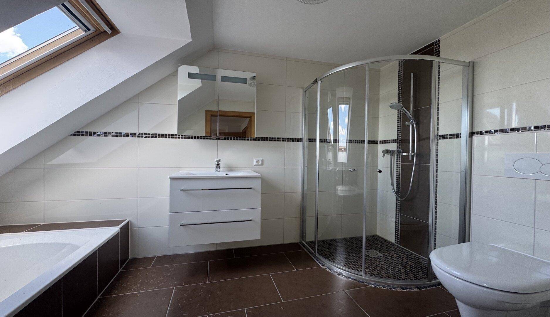 Modernes Badezimmer mit Dusche, Badewanne, Waschbecken und Dachfenster.
