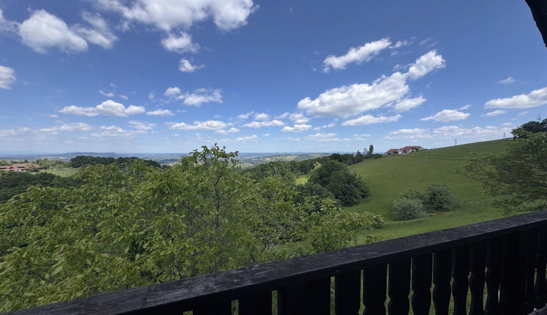 Panoramablick von einem Balkon über die grüne Hügellandschaft in der Ferne.