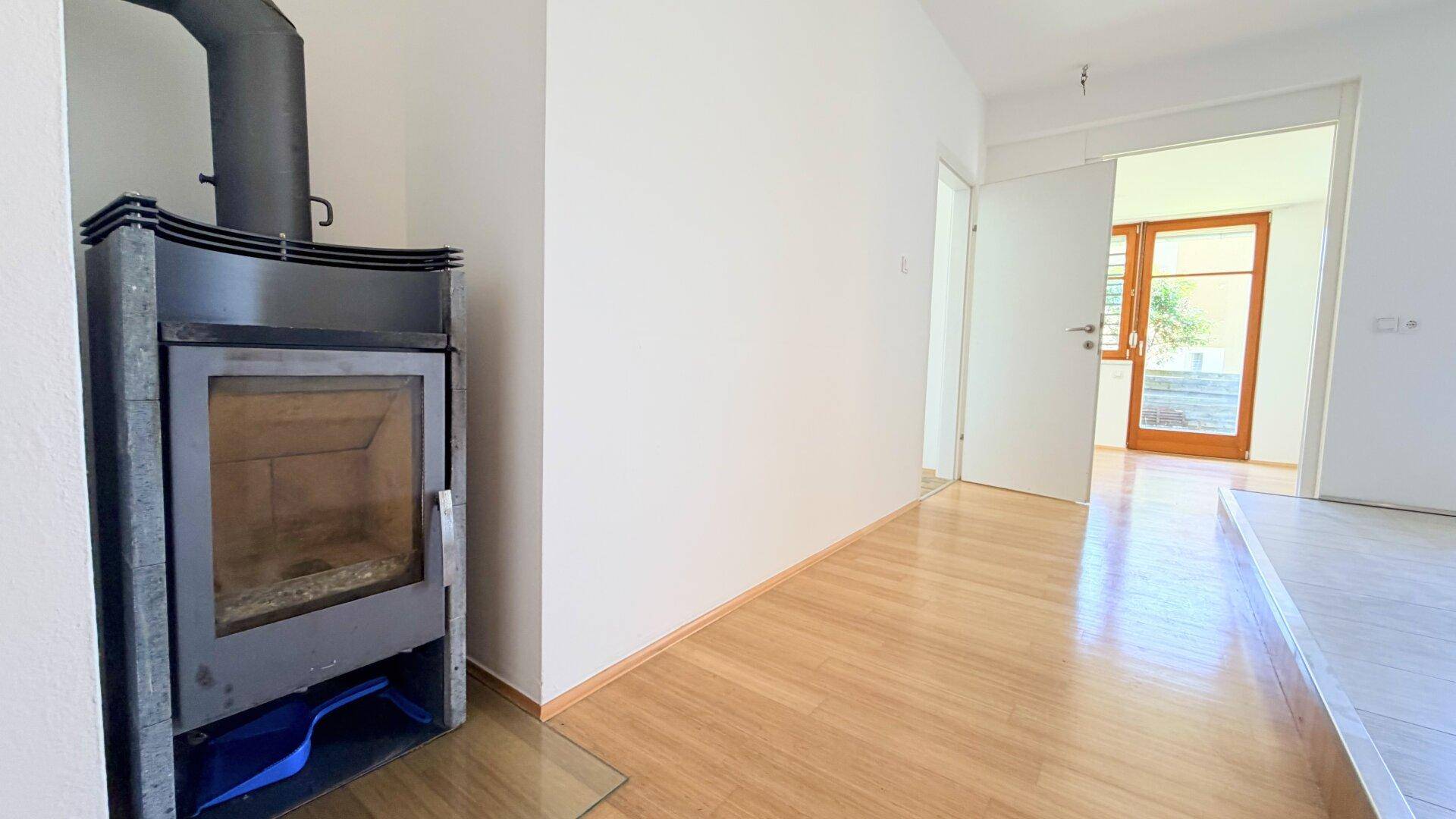 Gemütlicher Wohnbereich mit Holzfußboden und einem modernen Kaminofen für zusätzliche Wärme.
