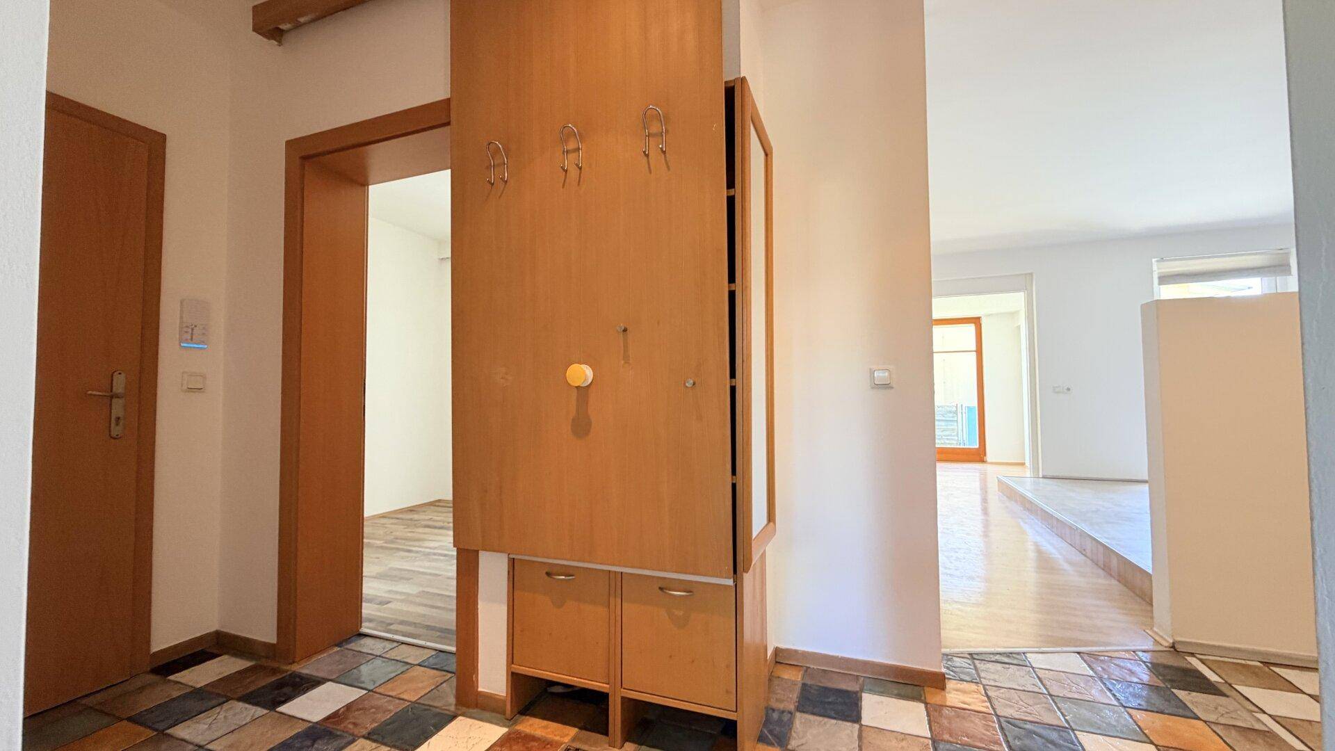 Flur mit farbenfrohem Fliesenboden und praktischer Garderobe mit Spiegel und Haken.