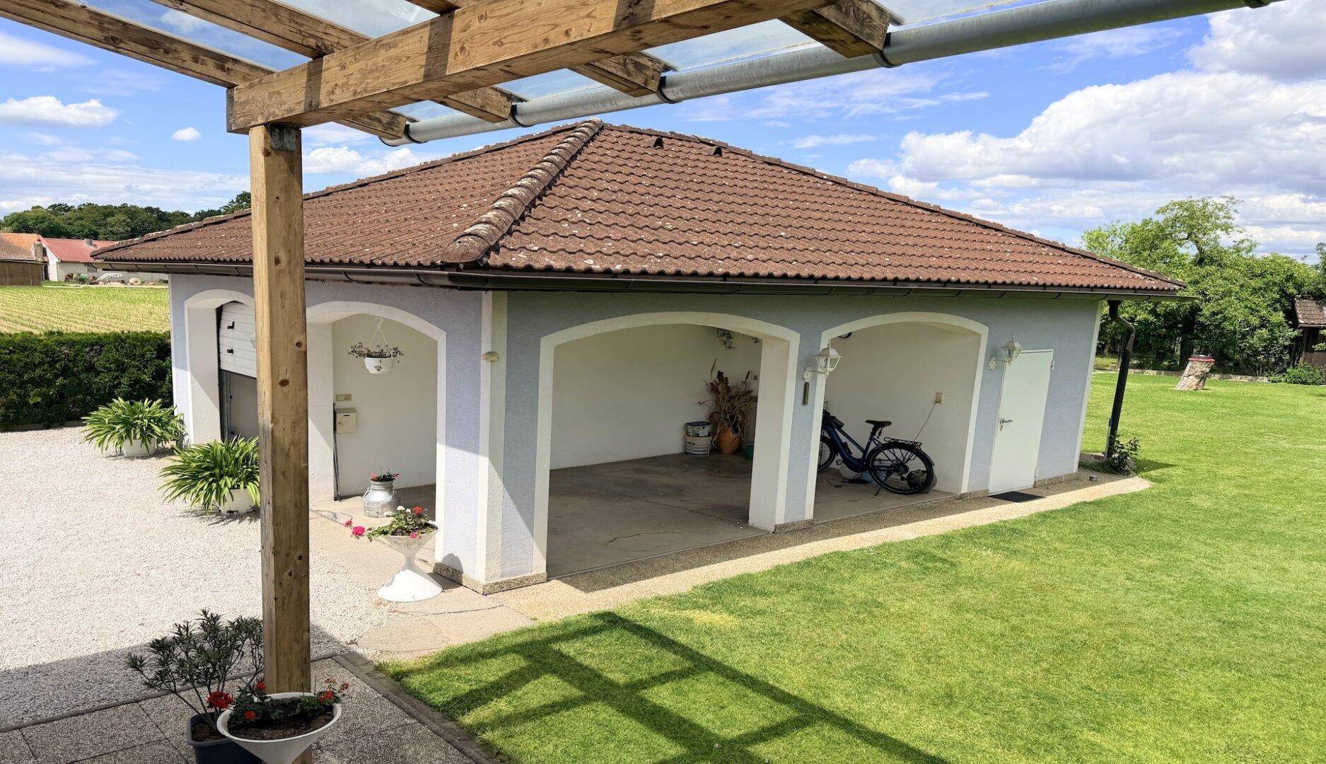 Überdachter Carport-Bereich mit zwei Stellplätzen und Zugang zum Garten.