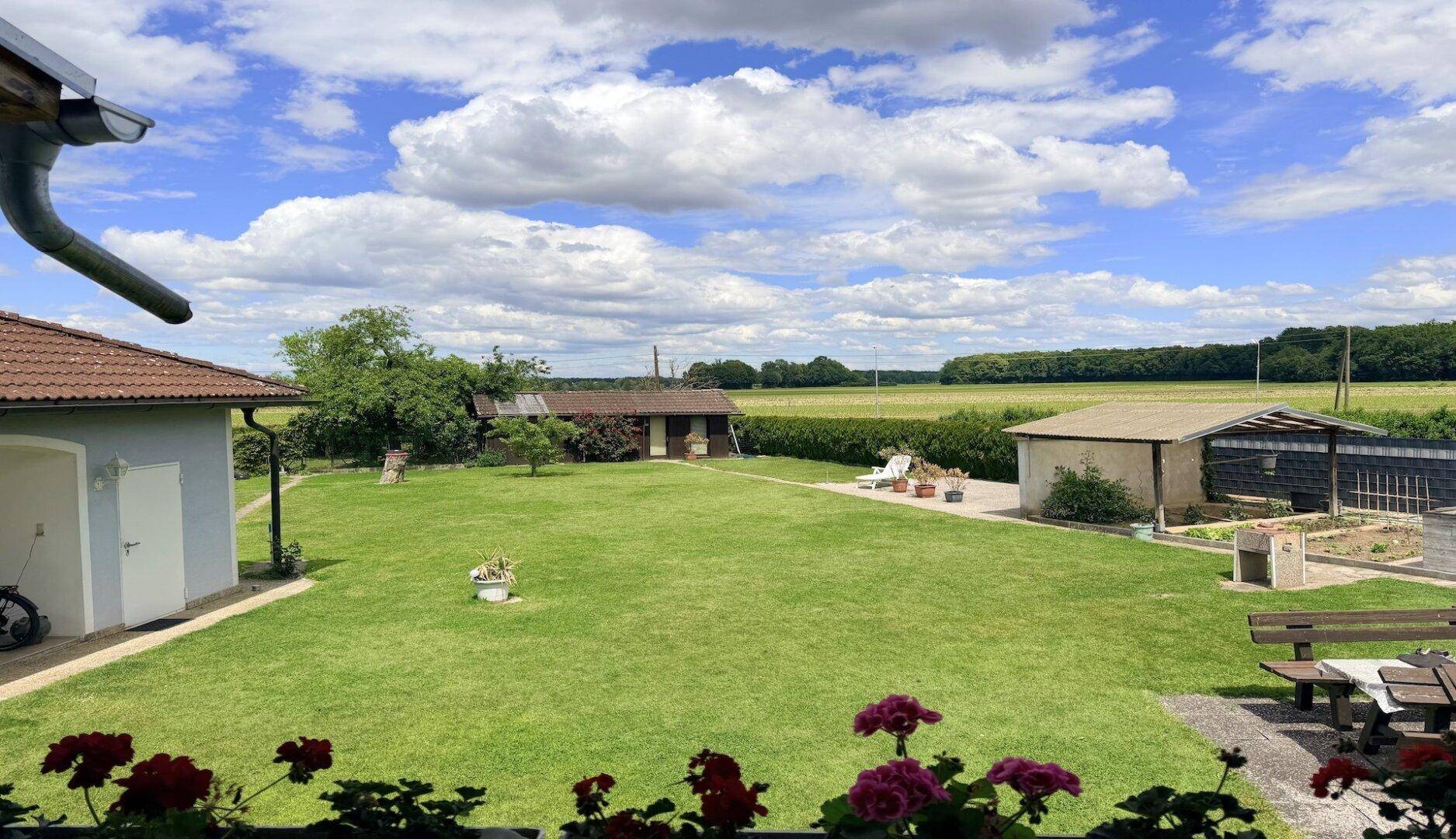 Weitläufiger Garten mit Rasenfläche, Sitzbereich und Blick auf die umliegende Landschaft.
