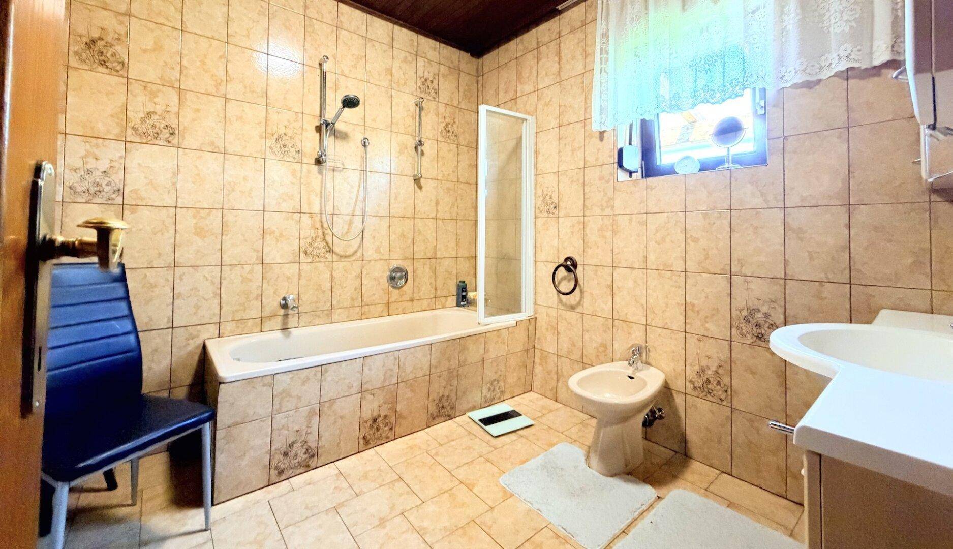 Badezimmer mit Badewanne, Bidet und beigefarbenen Fliesen im traditionellen Stil.