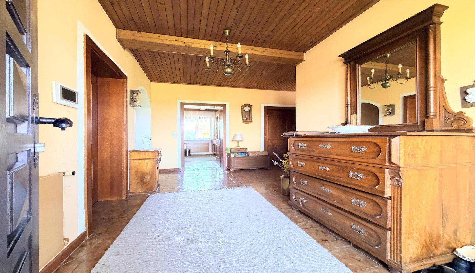 Geräumiger Flur mit Holzdecke, Fliesenboden und traditionellen Möbeln.