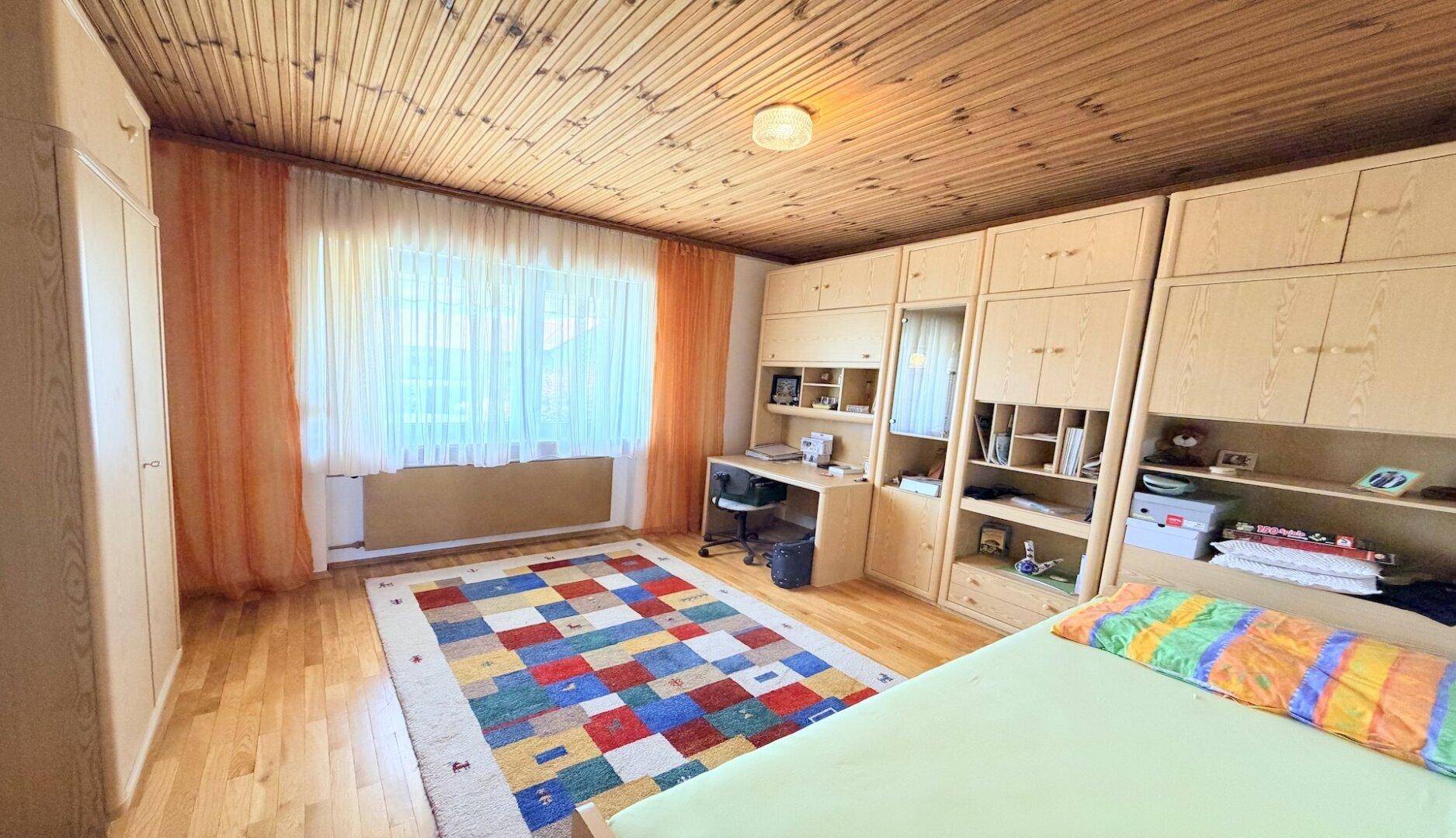Schlafzimmer mit Holzdecke, Einbauschränken und hellem Parkettboden.