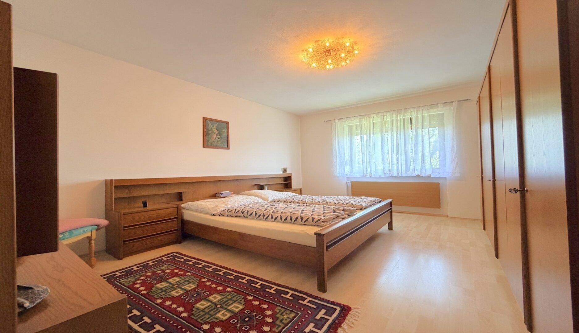 Schlafzimmer mit Doppelbett, Kleiderschränken und hellem Parkettboden.