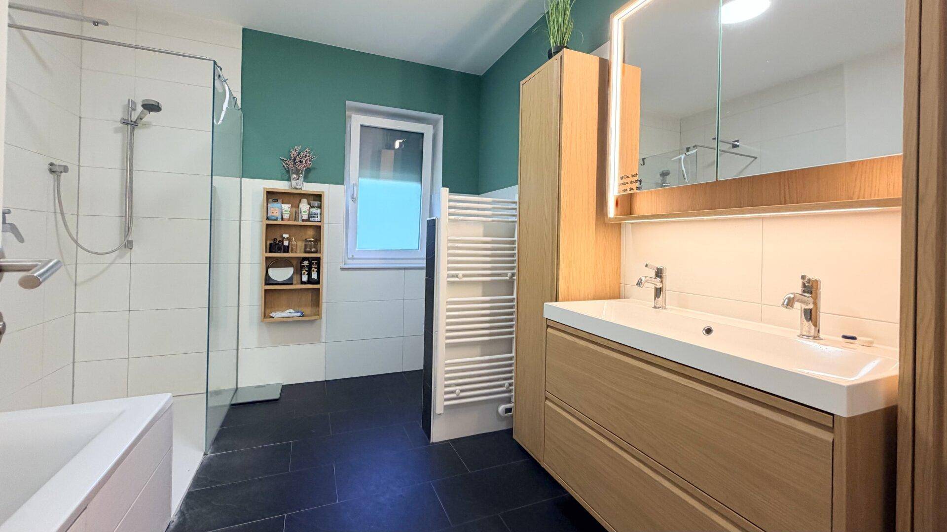 Modernes Badezimmer mit Doppelwaschbecken, Dusche, Badewanne und Fenster.