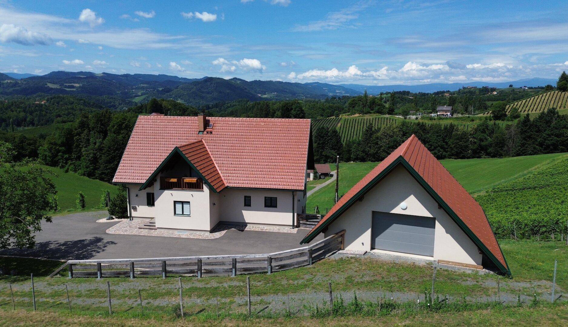 Das Anwesen mit Hauptgebäude und separater Garage, umgeben von einer idyllischen Weinlandschaft.