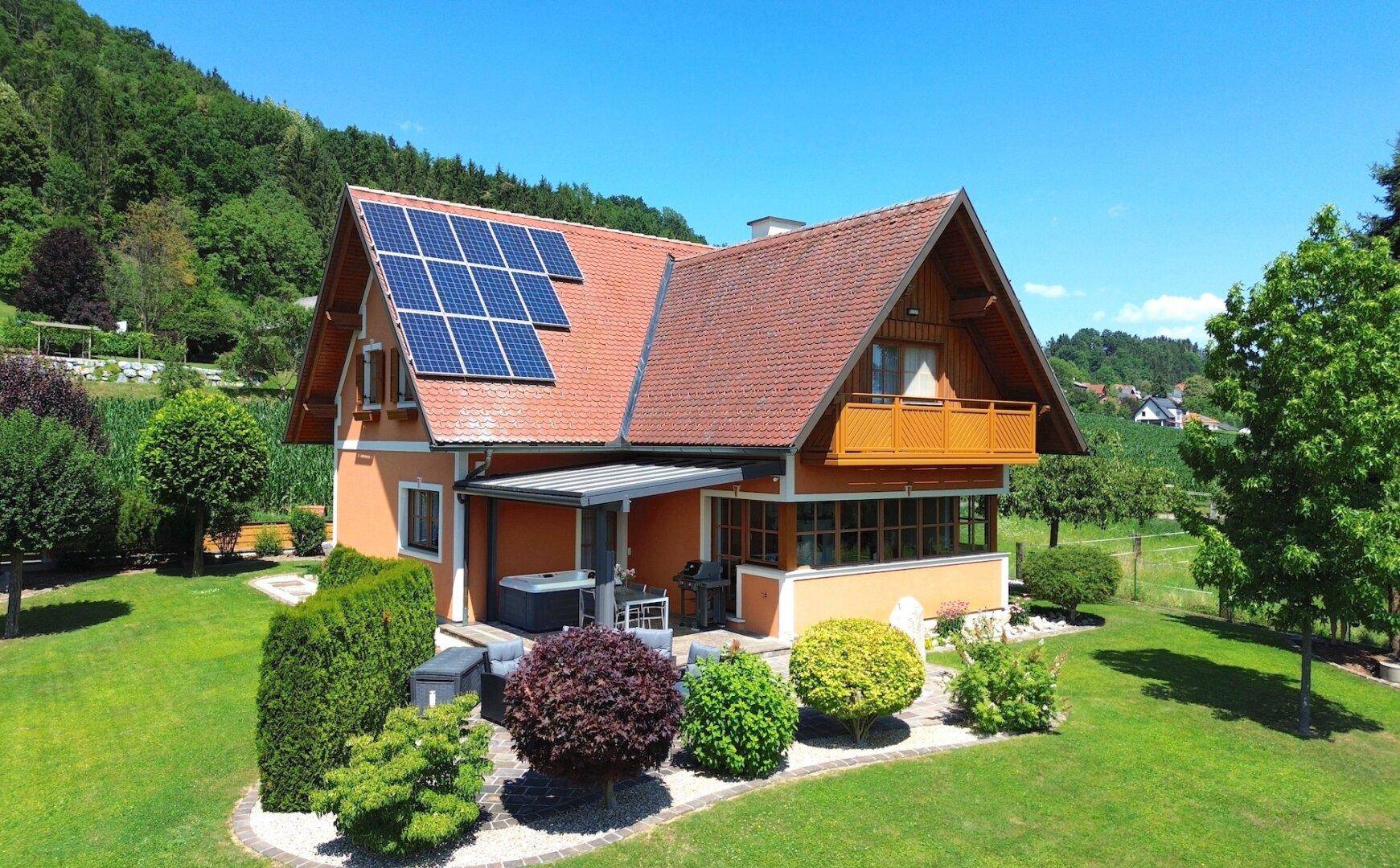 Luftaufnahme des Hauses mit großem Garten, Whirlpool und Photovoltaikanlage auf dem Dach.