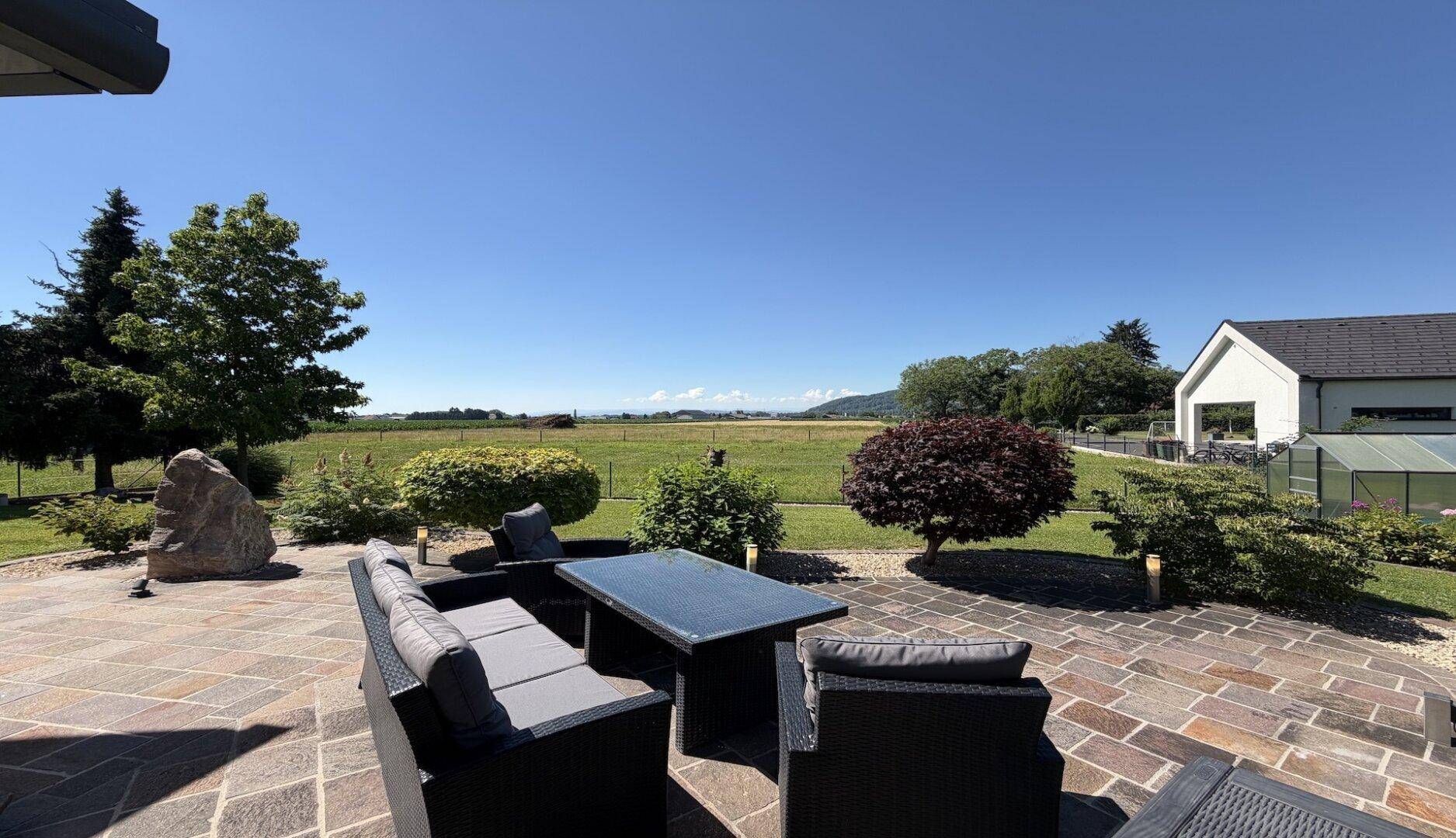 Gemütliche Terrasse mit modernen Gartenmöbeln und unverbautem Blick auf die Natur.